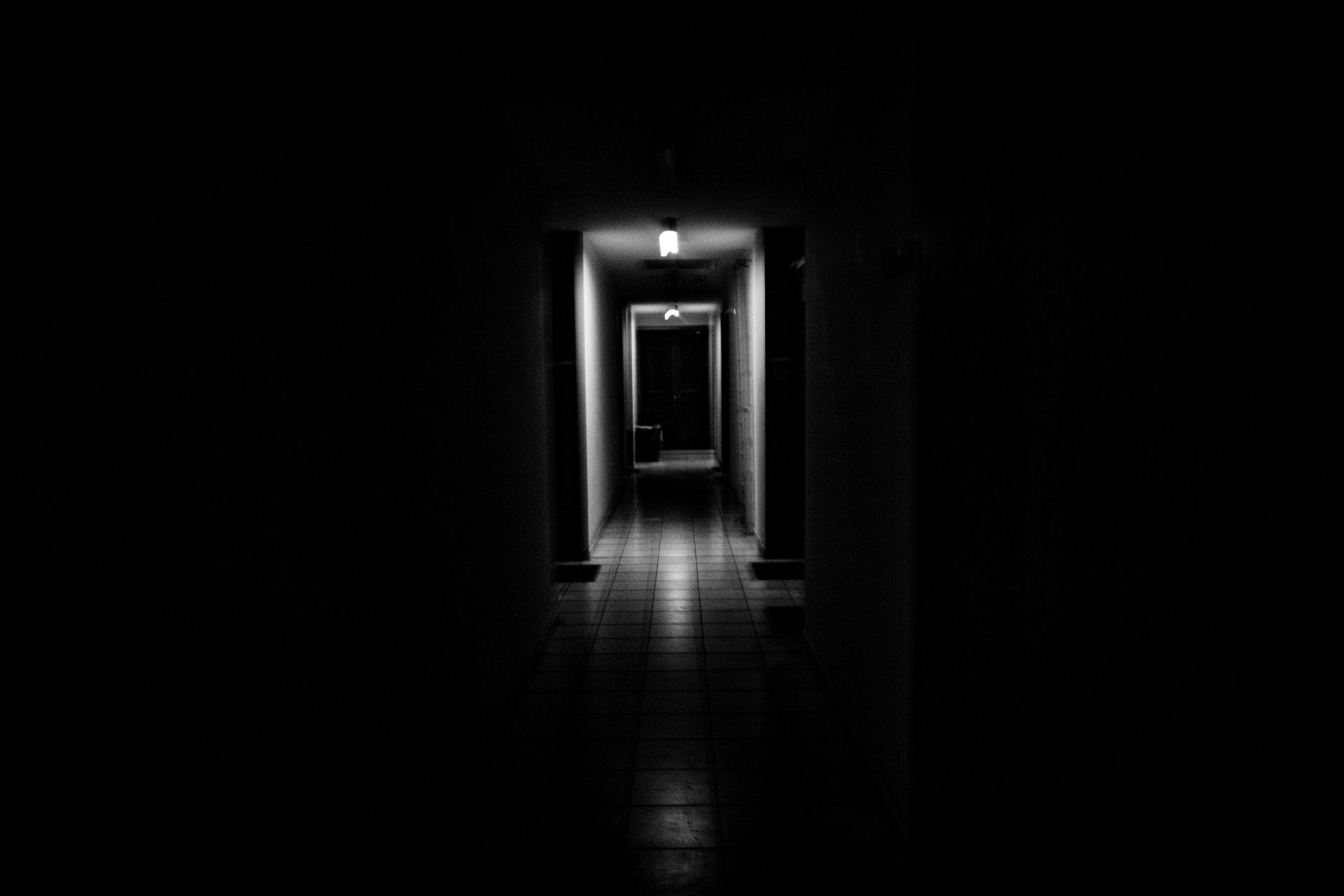 Dark hallway with a single light at the end.